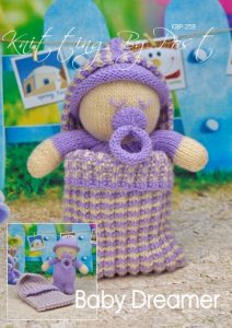 Baby Dreamer knitting pattern. Cream-colored knitted toy doll approximately 21cm long, featuring a purple onesie and a matching sleeping bag approximately 23cm long, perfect for bedtime play.