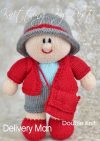 Postman knitting pattern. Cream-colored knitted toy doll approximately 30cm tall, featuring a red uniform, blue hat, and grey bag, inspired by the Royal Mail.