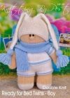 Ready for Bed Twin Boy knitting pattern. Cream-colored knitted toy doll approximately 28cm tall, featuring blue shorts, a matching hat, and a sleepy expression, embodying a bedtime theme.