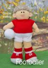 Footballer knitting pattern. Cream-colored knitted toy doll approximately 38cm tall, wearing a red and white football kit, brown hair, and holding a white football.
