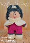 Amanda Doll knitting pattern. Cream-colored knitted toy doll approximately 30cm tall, featuring brown hair styled in a ponytail, a pink dress, and a fashionable shoulder cape.