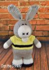 A play days pattern hand-knitted grey donkey toy with white muzzle, wearing a yellow jumper with black stripe, made using the Dan the Donkey knitting pattern.