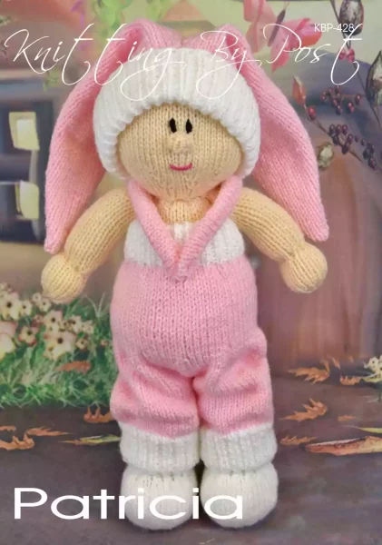 Patricia the Dolly knitting pattern. Cream-colored knitted toy doll approximately 33cm tall, featuring a removable pink hat and dungarees.