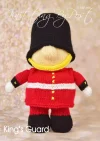 Kings Guard toy knitting pattern. Knitted figure representing a King's Guard, wearing a red tunic, black hat, and white belt, approximately 28cm tall.