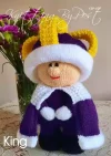 A Royal King toy knitting pattern figure representing a king wearing a purple robe with white trim and a yellow crown made from Royal King Toy Knitting Pattern