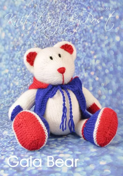 Gala Bear toy knitting pattern. Knitted white teddy bear with red and blue details, sitting at approximately 18cm tall.