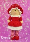 Scarlet the Dolly knitting pattern. Red knitted toy doll wearing a floppy hat and ruffled dress.