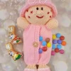 Yummy Tummy Dolly knitting pattern. Pink knitted doll with a round head, stitched facial features, and an opening in the tummy for storing sweet treats